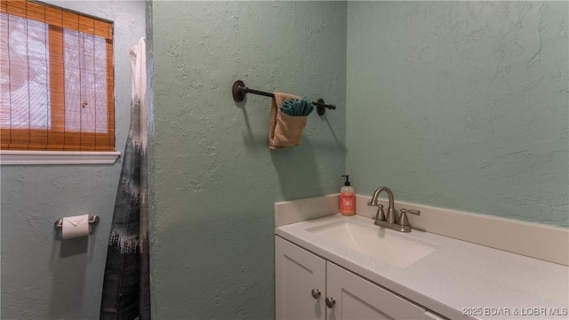 full bathroom featuring a healthy amount of sunlight, a textured wall, and a sink