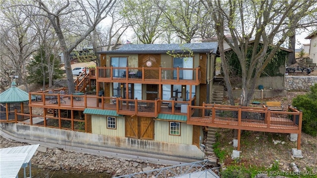 rear view of property featuring roof with shingles, a deck, and stairway