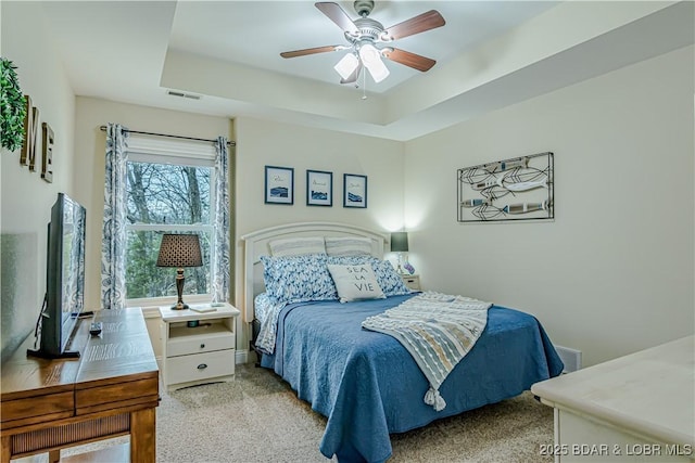 bedroom featuring carpet, a ceiling fan, and a raised ceiling