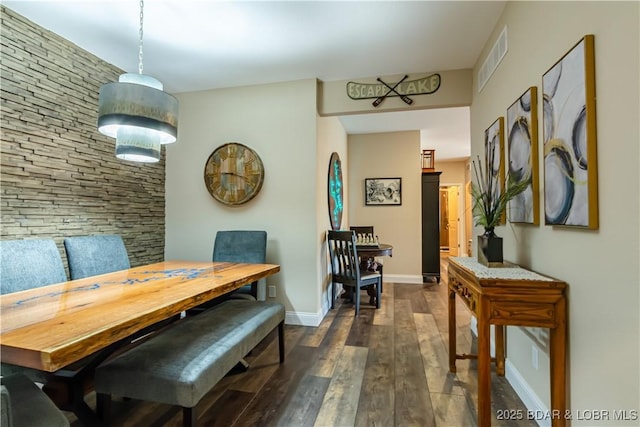 dining space featuring dark wood finished floors and baseboards