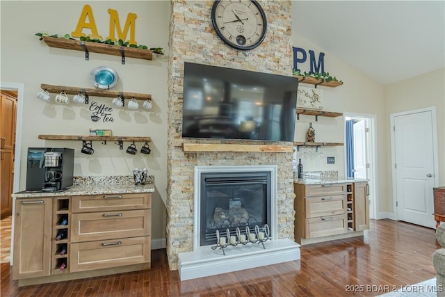 living area featuring vaulted ceiling, dark wood-style floors, and a fireplace