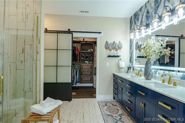 full bathroom featuring wood finished floors, a spacious closet, double vanity, and baseboards
