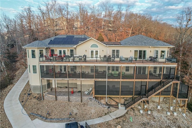 back of property with french doors, solar panels, a patio, stairs, and a wooden deck