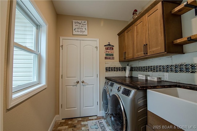 clothes washing area featuring washer and clothes dryer, cabinet space, and baseboards