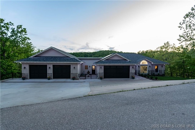 view of front facade featuring an attached garage, concrete driveway, and stone siding