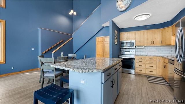 493 Highline Rd, Lake Ozark, MO 65049 - kitchen with appliances with stainless steel finishes, light brown cabinets, light wood-style floors, decorative backsplash, and a breakfast bar