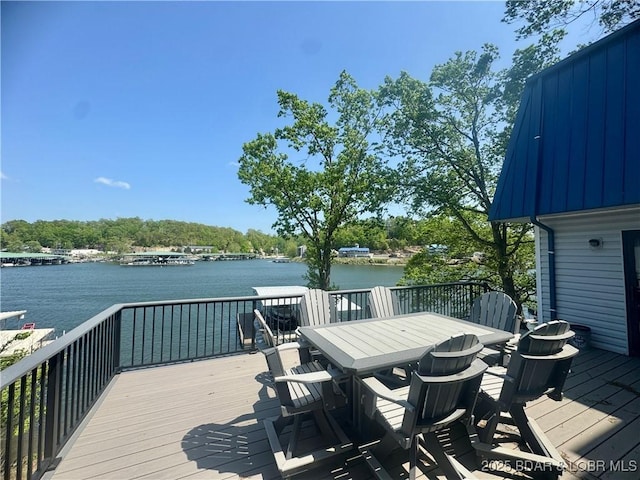 deck with outdoor dining area and a water view