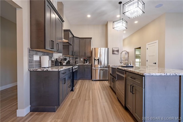 613 Cove Cir, Sunrise Beach, MO 65079 - kitchen with appliances with stainless steel finishes, light wood-style flooring, dark brown cabinets, light stone countertops, and recessed lighting