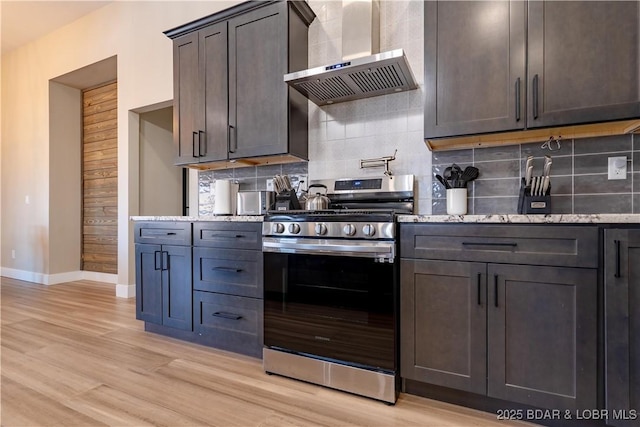 613 Cove Cir, Sunrise Beach, MO 65079 - kitchen with stainless steel gas range oven, wall chimney exhaust hood, light wood finished floors, and light stone counters