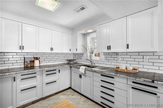 31372 Golden Wood Rd, Gravois Mills, MO 65037 - kitchen with light wood-style floors, white cabinets, visible vents, a sink, and decorative backsplash