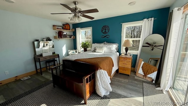 bedroom featuring baseboards, multiple windows, wood finished floors, and a ceiling fan