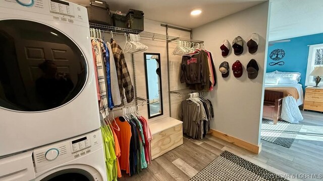 washroom featuring baseboards, stacked washing maching and dryer, laundry area, recessed lighting, and light wood finished floors