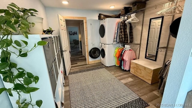 laundry room with laundry area, wood finished floors, and stacked washer and clothes dryer