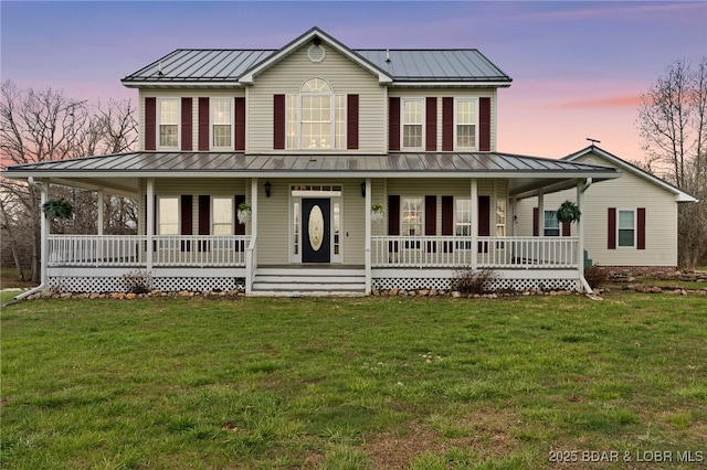 farmhouse-style home with a front yard, metal roof, covered porch, and a standing seam roof
