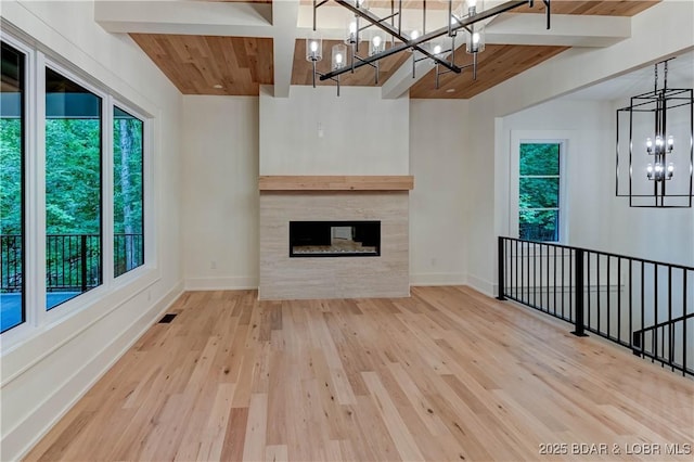 320 Via Appia Dr, Sunrise Beach, MO 65079 - unfurnished living room featuring a chandelier, wood ceiling with exposed beams, baseboards, wood finished floors, and a tile fireplace