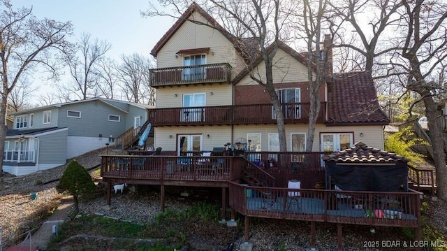 back of house with stairs, a balcony, and a wooden deck