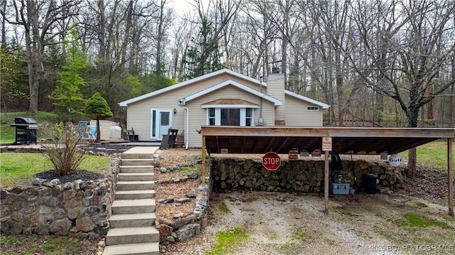 view of front of home with a carport, a chimney, and driveway