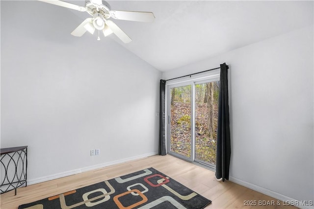 empty room with wood finished floors, ceiling fan, baseboards, and vaulted ceiling