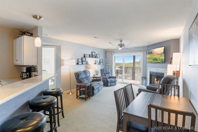 222 Park Place Ln Unit 2A, Kaiser, MO 65047 - living area featuring light colored carpet, a warm lit fireplace, and a ceiling fan