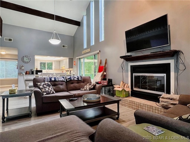 1505 Swiss Village Rd Unit A5, Osage Beach, MO 65065 - living room featuring wood finished floors, high vaulted ceiling, a glass covered fireplace, and beam ceiling