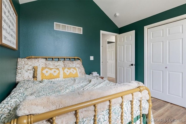 bedroom with visible vents, wood finished floors, and lofted ceiling