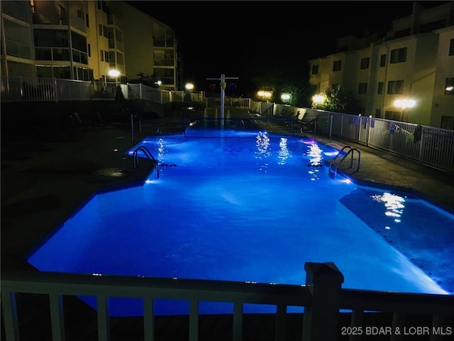 pool at twilight with a community pool and fence