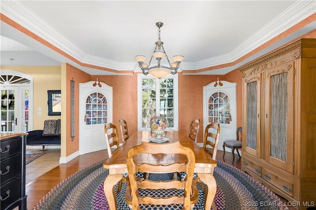 dining room with a chandelier, wood finished floors, crown molding, and baseboards
