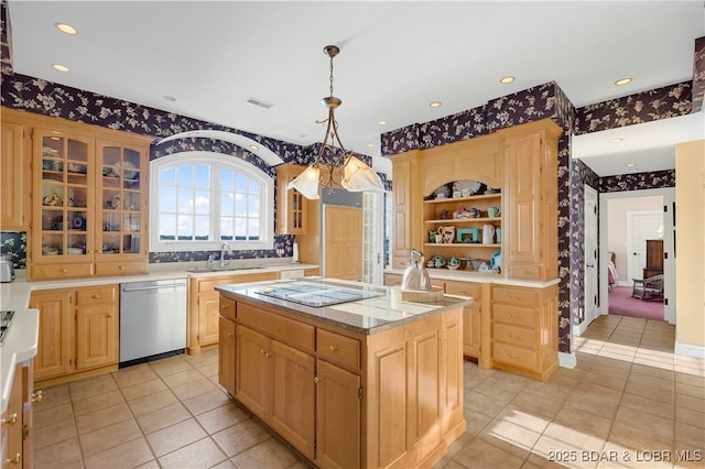 kitchen with stainless steel dishwasher, wallpapered walls, a sink, cooktop, and light brown cabinets