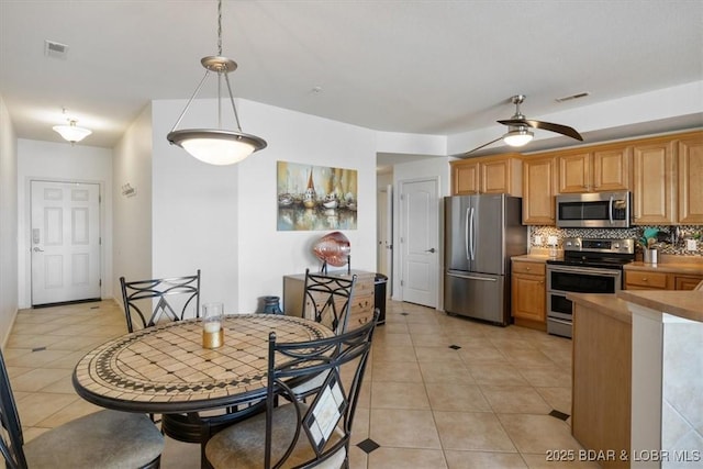 1205 Lands End Pkwy Unit 533, Osage Beach, MO 65065 - kitchen featuring appliances with stainless steel finishes, light tile patterned floors, tasteful backsplash, a ceiling fan, and decorative light fixtures