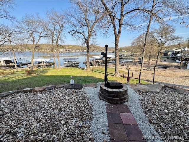 view of grassy yard featuring a fire pit and a water view