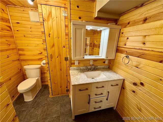 half bathroom featuring wooden walls, toilet, vanity, and tile patterned floors