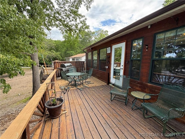 wooden deck featuring outdoor dining area and a grill