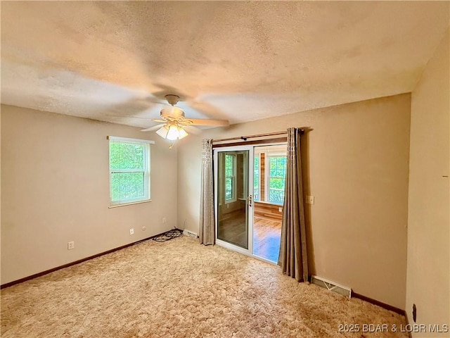 carpeted empty room with a textured ceiling, a ceiling fan, and baseboards