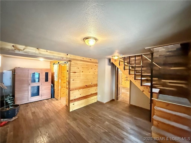21 Ke Jo Point Rd, Gravois Mills, MO 65037 - unfurnished living room featuring stairs, wood walls, wood finished floors, a textured ceiling, and a barn door