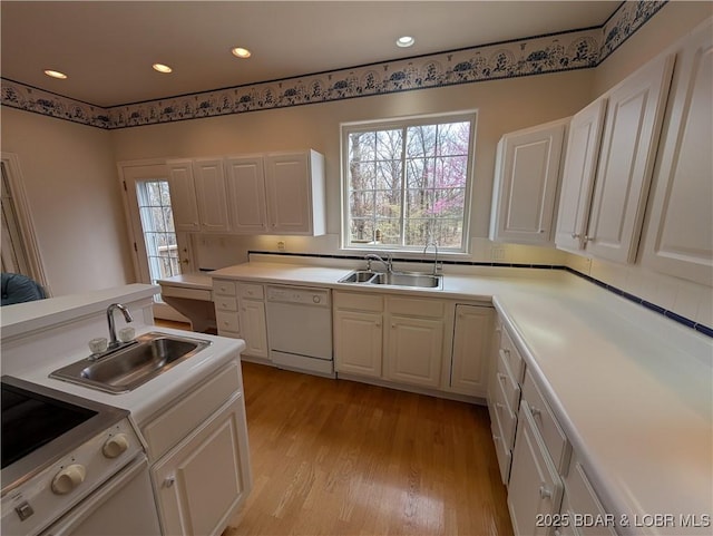 kitchen featuring a sink, white appliances, light wood-style flooring, and white cabinetry
