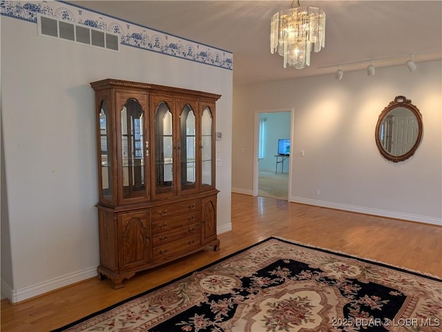 hallway featuring visible vents, a chandelier, track lighting, and light wood-type flooring