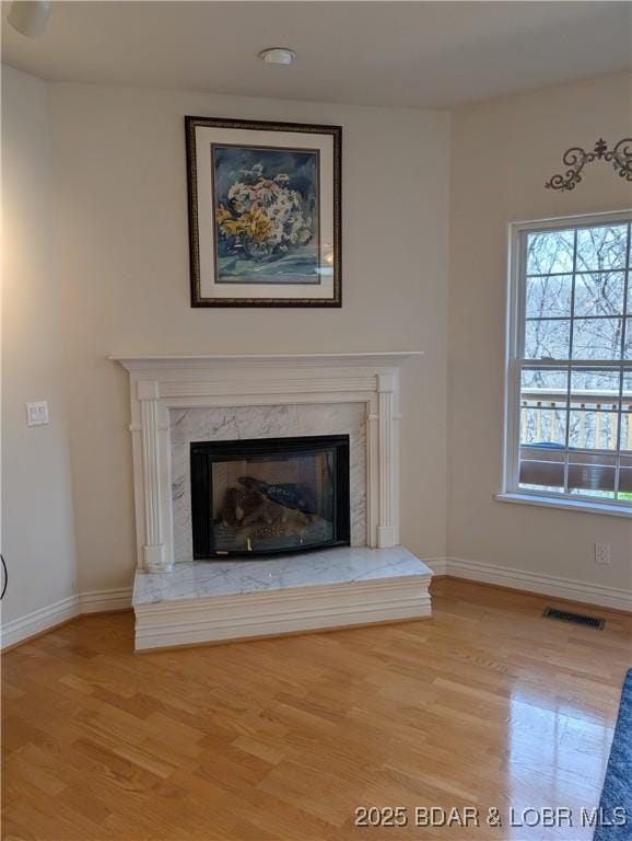 details featuring baseboards, visible vents, wood finished floors, and a fireplace