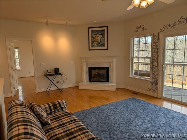 living area featuring a ceiling fan, visible vents, a high end fireplace, rail lighting, and wood finished floors