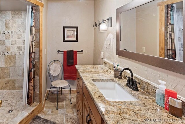 32785 Dixie Dr, Gravois Mills, MO 65037 - full bath with vanity, a stall shower, stone finish flooring, and a textured wall