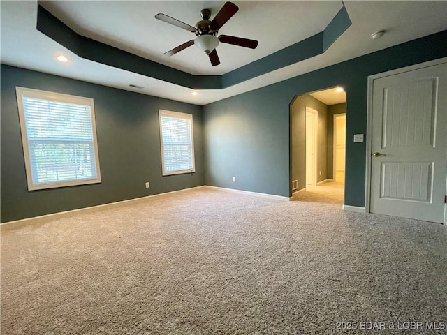1148 Sweetwater Dr, Four Seasons, MO 65049 - carpeted empty room with visible vents, baseboards, arched walkways, a tray ceiling, and a ceiling fan