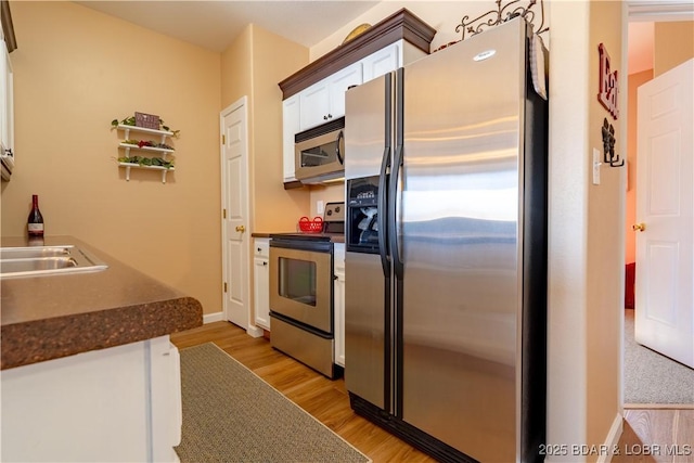 275 Flynn Rd Unit 205, Lake Ozark, MO 65049 - kitchen featuring white cabinetry, light wood-style flooring, dark countertops, and stainless steel appliances