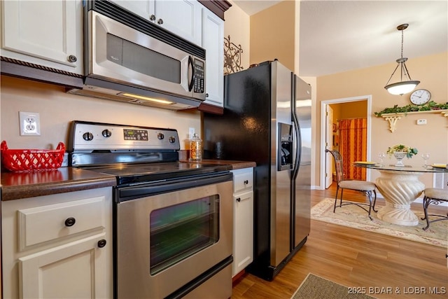 275 Flynn Rd Unit 205, Lake Ozark, MO 65049 - kitchen with white cabinets, decorative light fixtures, dark countertops, light wood-style floors, and stainless steel appliances