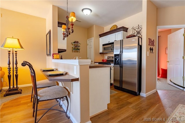 275 Flynn Rd Unit 205, Lake Ozark, MO 65049 - kitchen featuring light wood-style flooring, hanging light fixtures, white cabinets, and stainless steel appliances
