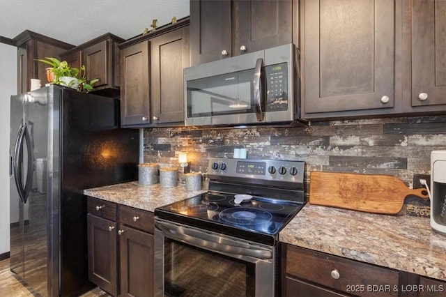 kitchen with appliances with stainless steel finishes, dark brown cabinetry, decorative backsplash, and light stone counters