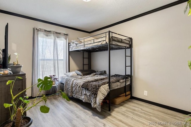 bedroom featuring ornamental molding, light wood-style floors, and baseboards