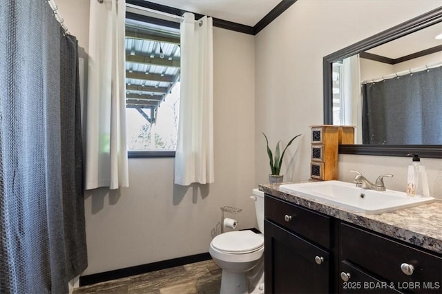 bathroom with crown molding, wood finished floors, toilet, vanity, and baseboards