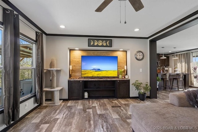 living room with ornamental molding, wood finished floors, baseboards, ceiling fan, and recessed lighting