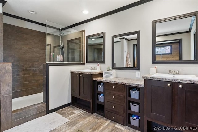full bathroom featuring crown molding, walk in shower, two vanities, wood finished floors, and recessed lighting