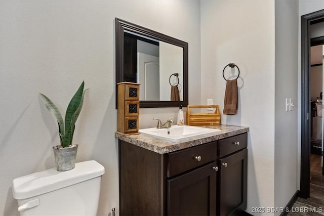 half bath with vanity, toilet, and wood finished floors