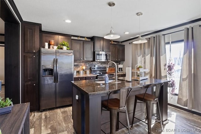 kitchen with appliances with stainless steel finishes, a sink, dark brown cabinets, light wood-style floors, and recessed lighting